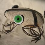 Big Eyed Frog.  Flat cobbles used for the body with rusty metal used for the legs.  Glass fused eyes attached to the head bring it to life.