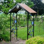 Bubble Trellis has circles attached to the metal frame and powder coated black with fused glass attached in some of the circles.  A variety of butterflies are the theme in the circles with various flowers.  Looking thru the trellis you will see another film trellis with purple iris and hummingbirds.