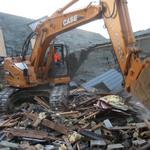 Excavator clawing down the shop.
