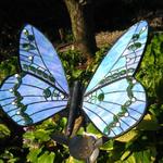 Iridescent  light blue glass butterfly with green and white gems throughout the design with wing span of 28 inches. Fastened to a metal milkweed plant, allowing mother nature to rust it naturally. 